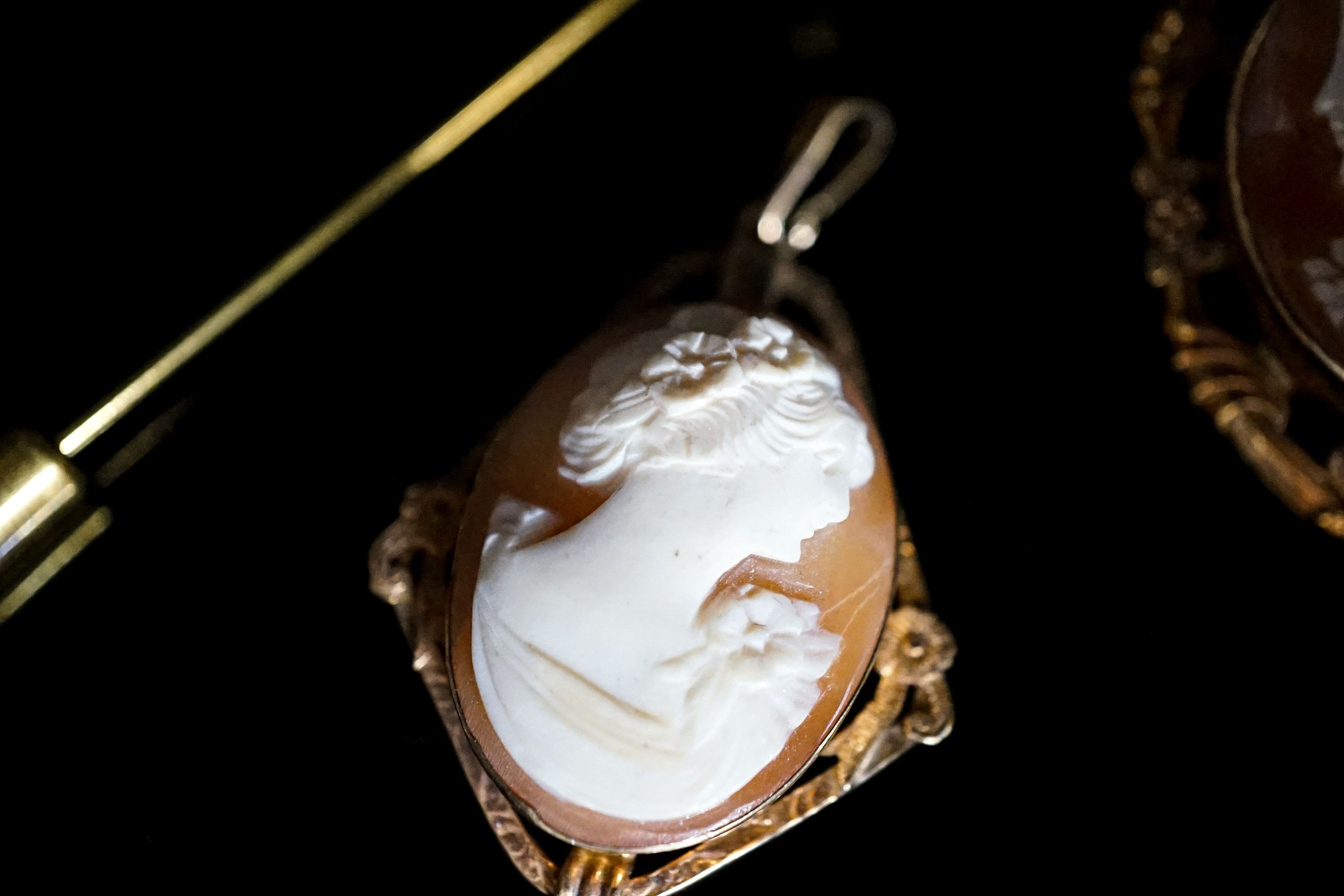 Two mounted cameo shell pendants, one with brooch attachment and a gilt metal cameo pin.